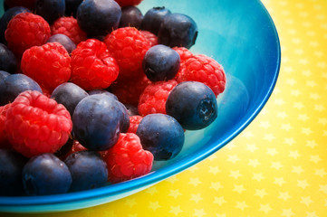 blue bowl with fruit berries - raspberries and blueberries in a bowl