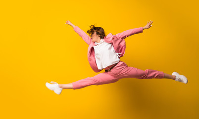 Young woman jumping over isolated yellow wall