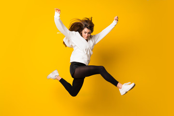 Young woman jumping over isolated yellow wall