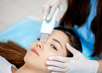 cosmetologist with a patient during facial procedures in a modern cosmetological and aesthetic clinic. A patient receives an electric facial massage. Skin rejuvenation and wrinkle smoothing.