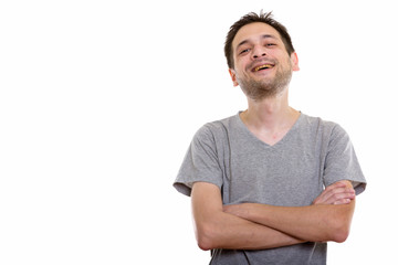 Studio shot of happy young man smiling and laughing with arms cr