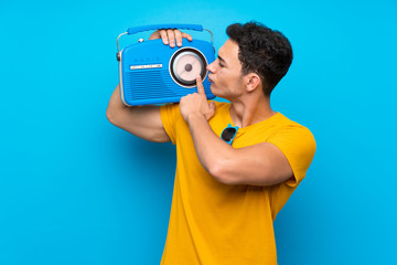 Handsome man over blue background holding a radio