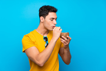 Handsome man over blue background with a coconut