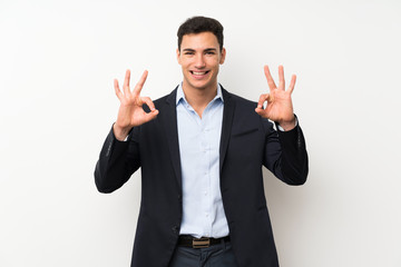Handsome man over isolated white wall showing an ok sign with fingers