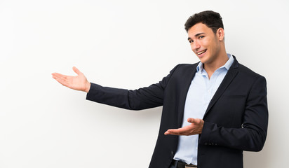 Handsome man over isolated white wall extending hands to the side for inviting to come