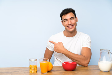 Handsome man in having breakfast pointing finger to the side