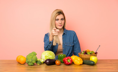 Fototapeta premium Young blonde woman with many vegetables frustrated and pointing to the front