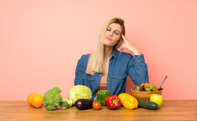 Fototapeta premium Young blonde woman with many vegetables with problems making suicide gesture