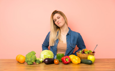 Young blonde woman with many vegetables suffering from backache for having made an effort