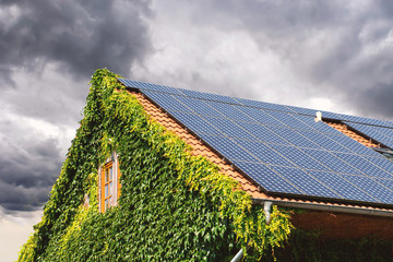 Solarplatten auf Wohnhaus vor wolkigem Himmel