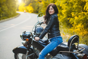 Fototapeta na wymiar attractive brunette motorcyclist sits on a motorcycle. adventure concept
