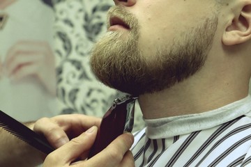 Barber shaves beard of client man on chair Barbershop. Beard Haircut. barber shaving beard with...
