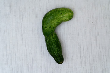 Mishappen cucumber  on rustic table. Cucumber as question mark