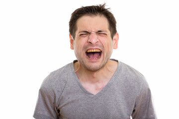 Studio shot of angry young man screaming with eyes closed