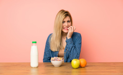 Young blonde woman with bowl of cereals nervous and scared
