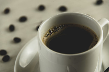 Front view of a delicious and tasty cup of freshly made coffee with coffee beans
