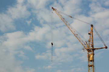 Industrial construction building crane against blue cloudy sky