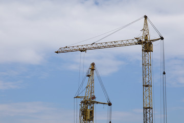 Fototapeta na wymiar Industrial construction building cranes against blue cloudy sky