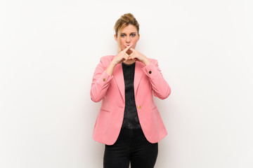 Young blonde woman with pink suit showing a sign of silence gesture