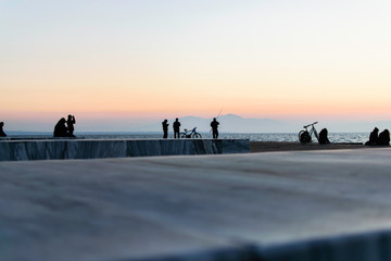 People sitting in the pier in Thessaloniki, Greece. Watching the sunset and talking to each other