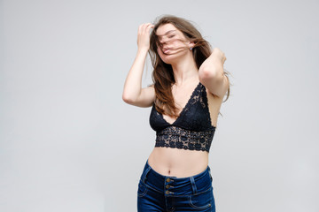 Photo portrait of a beautiful smiling brunette woman girl on a white background in jeans and a blouse with long beautiful flowing dark hair in the studio.