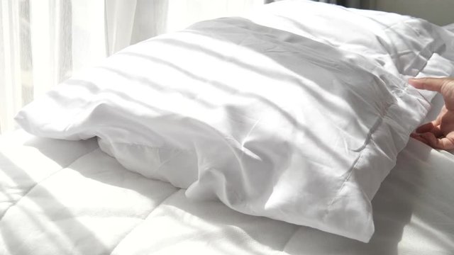 Hands bedding white blanket with natural light from window, slow motion