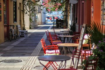Fototapeta na wymiar Empty street cafe with bright red chairs in hot summer day, Nafplio city, Greece 