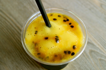 Glass of Mouthwatering Mango with Passion Fruit Smoothie on Wooden Table