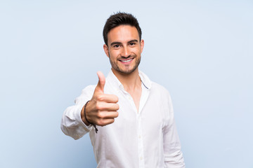 Handsome young man over isolated blue background with thumbs up because something good has happened