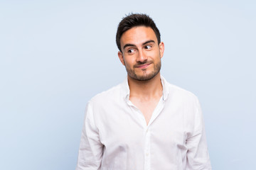 Handsome young man over isolated blue background making doubts gesture looking side