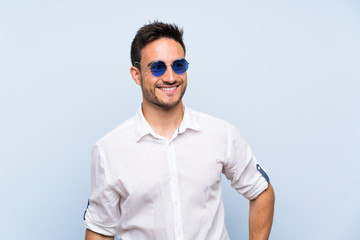 Handsome young man over isolated blue background with glasses and happy