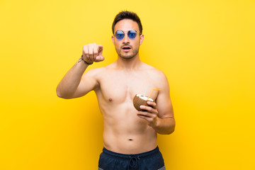 Handsome young man in summer clothes surprised and pointing front