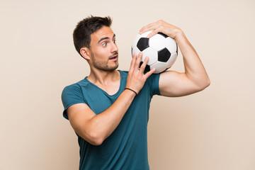 Handsome sport man over isolated background holding a soccer ball