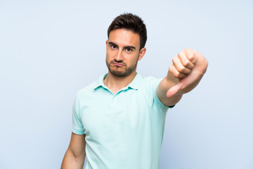 Handsome young man over isolated background showing thumb down with negative expression