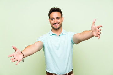 Handsome young man over isolated background presenting and inviting to come with hand