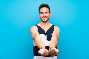 Handsome young man over isolated background holding copyspace imaginary on the palm to insert an ad