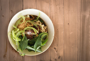 Chicken noodel with hot soup with herb on wood table