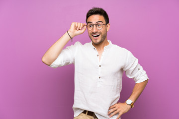 Handsome young man over isolated background with glasses and surprised