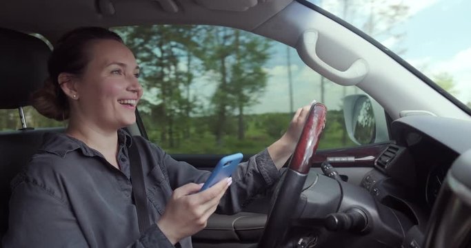 Woman gets into an accident on the car.  Dangerous situation on the road. Woman drives the car and typing text on the smartphone. Adult Woman in the car using mobile phone while driving. Real time.