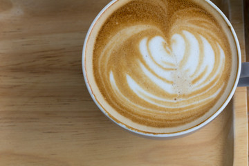 Cup of coffee is beautifully decorated, Coffee cup and coffee beans on a wooden table.