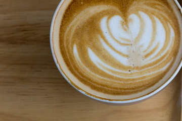 Cup of coffee is beautifully decorated, Coffee cup and coffee beans on a wooden table.