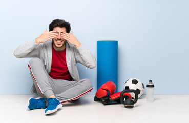 Sport man sitting on the floor covering eyes by hands