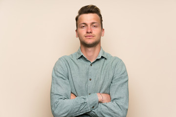 Blonde handsome man over isolated wall keeping arms crossed
