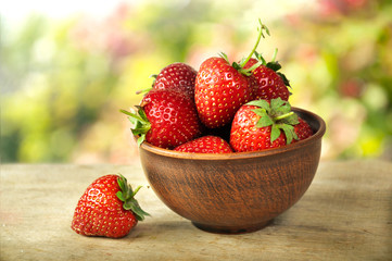 Ripe strawberries in ceramic ware on a wooden table. Summer berry vitamin dessert.