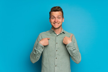 Blonde man over isolated blue wall with surprise facial expression