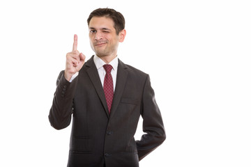 Studio shot of young businessman pointing finger up while winkin