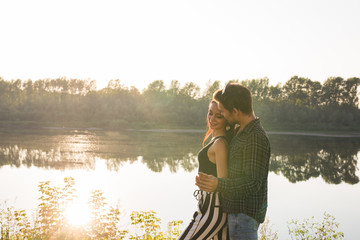 People, love and nature concept - Portrait of young beautiful couple embracing each other while standing over nature background
