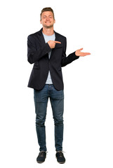 Blonde handsome man holding copyspace imaginary on the palm to insert an ad