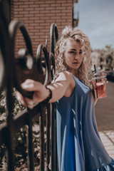 Stylish young beautiful girl posing on city street. Young blonde woman in sundress fashion lifestyle. Urban. Freedom moment. Summer time