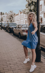 Naklejka premium Girl street style. Fashion young beautiful woman posing on city street. Urban. Sundress. Lifestyle. Moment. Holidays. Summer time